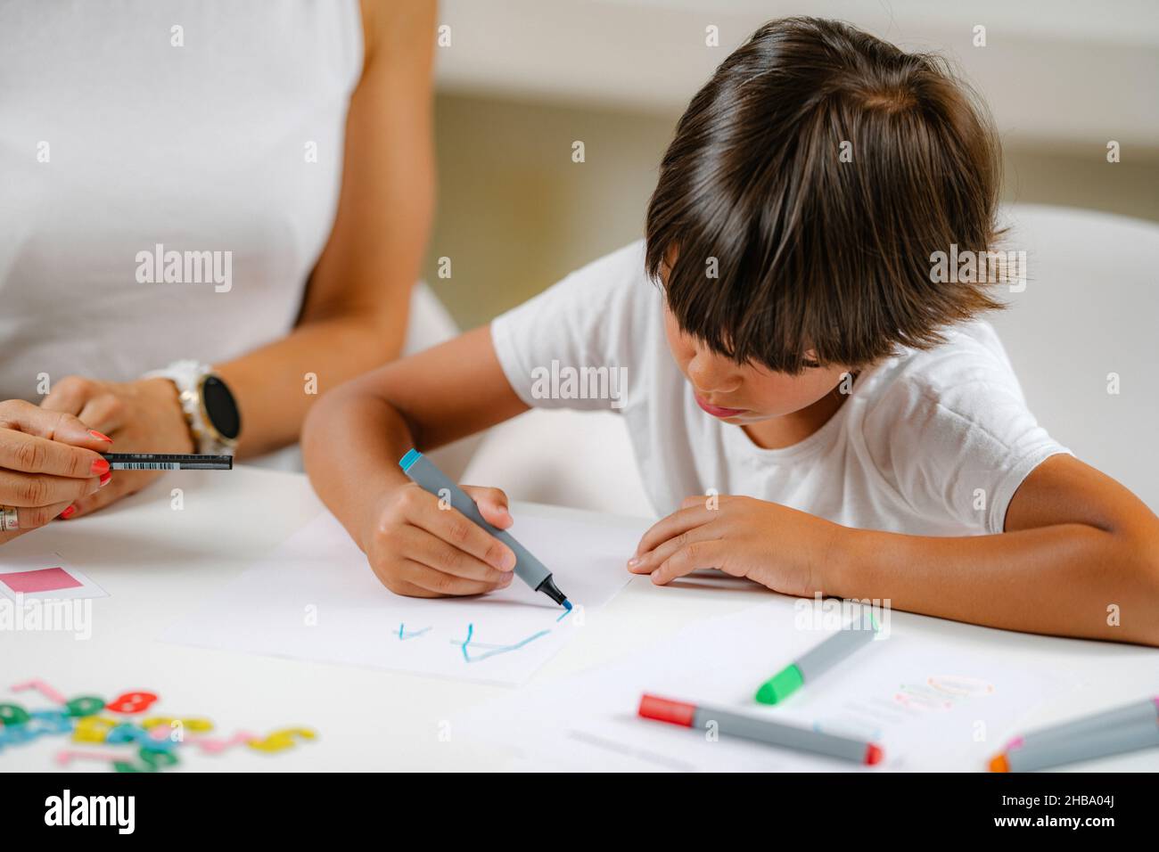 Garçon écrivant des lettres dans un test de dépistage préscolaire. Banque D'Images