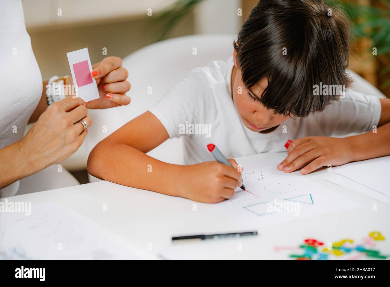 Enfant dessinant des formes dans une évaluation pré-scolaire, aide de psychologue. Banque D'Images
