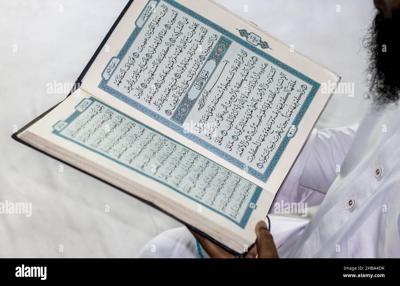Un musulman lisant Saint al coran dans sa main Banque D'Images