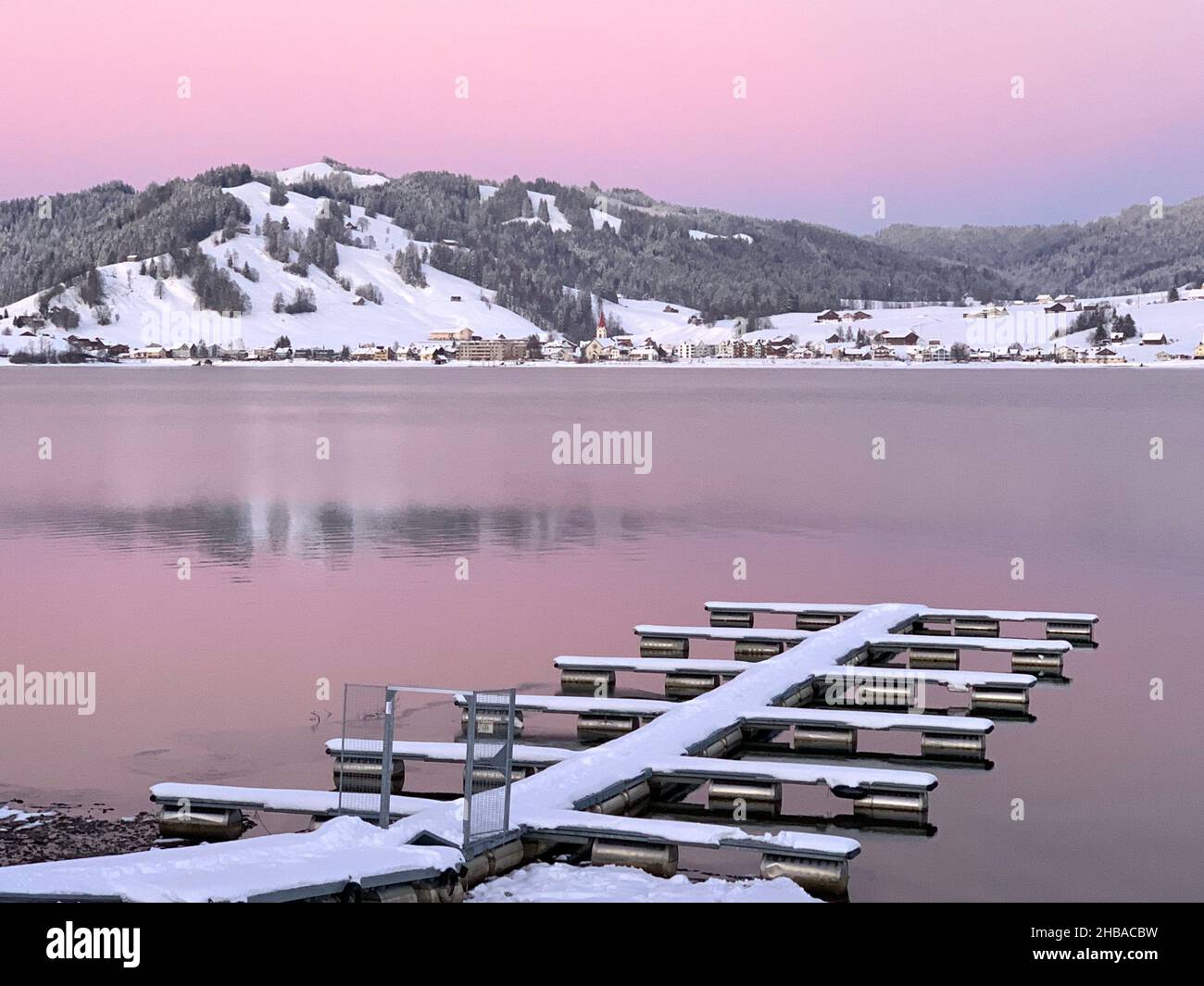 Coucher de soleil sur le lac Sihlsee en Suisse, canton de Schwyz, par une journée d'hiver claire.Il y a un lieu d'amarrage vide pour les bateaux couverts de neige. Banque D'Images