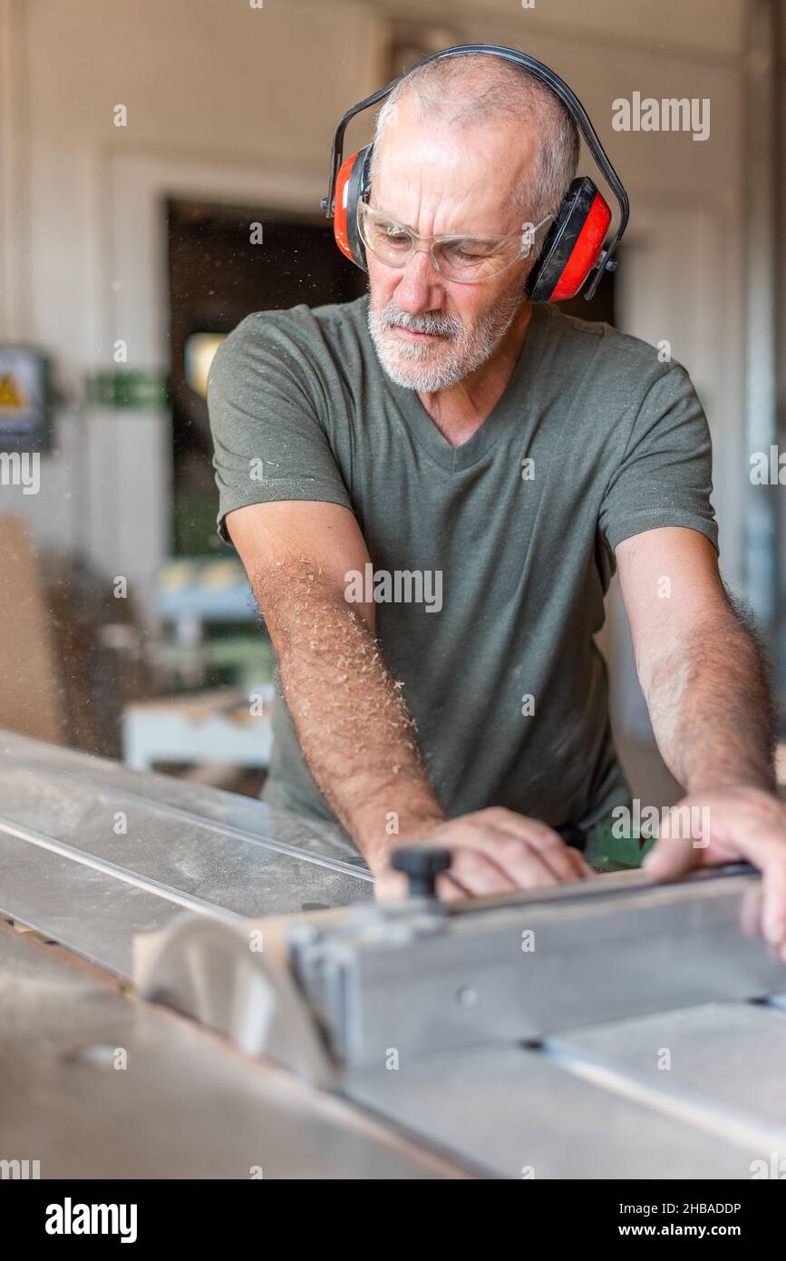 Homme travaillant sur une scie à table coulissante Banque D'Images