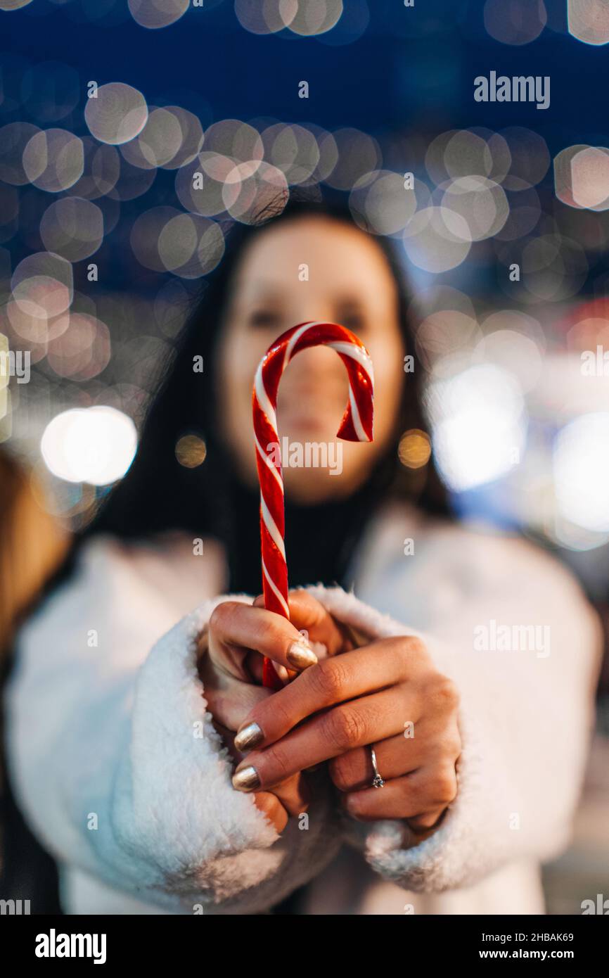 Main femelle tenant rouge blanc canne douce lollipop.Détails des vacances de Noël Banque D'Images