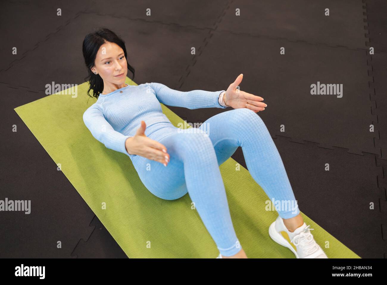 Femme en bleu sport faisant des exercices abdominaux assis tout en étant allongé sur le tapis sur le sol de la salle de sport Banque D'Images