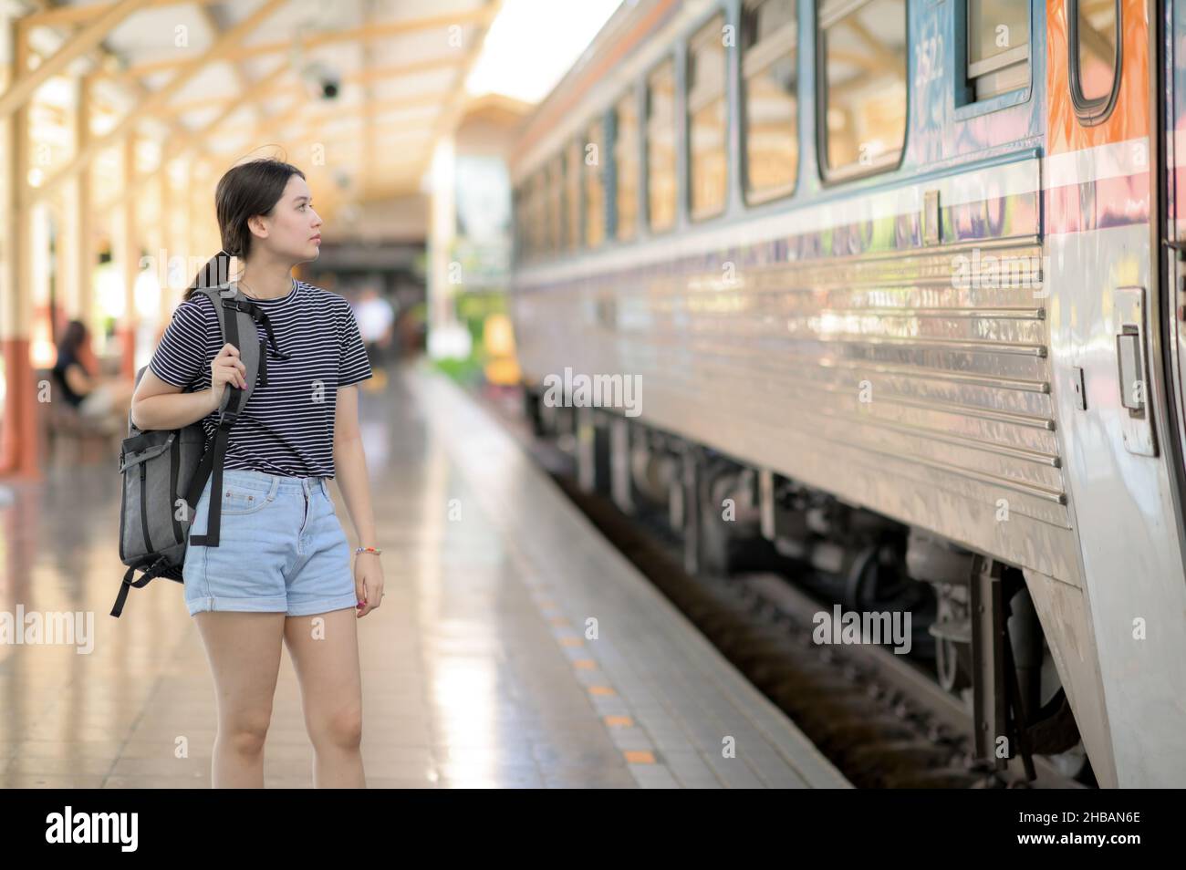 Une femme internationale voyageur avec un sac à dos attend le train, une adolescente se tient sur le bord d'une plate-forme attendant une voiture, une internement Banque D'Images