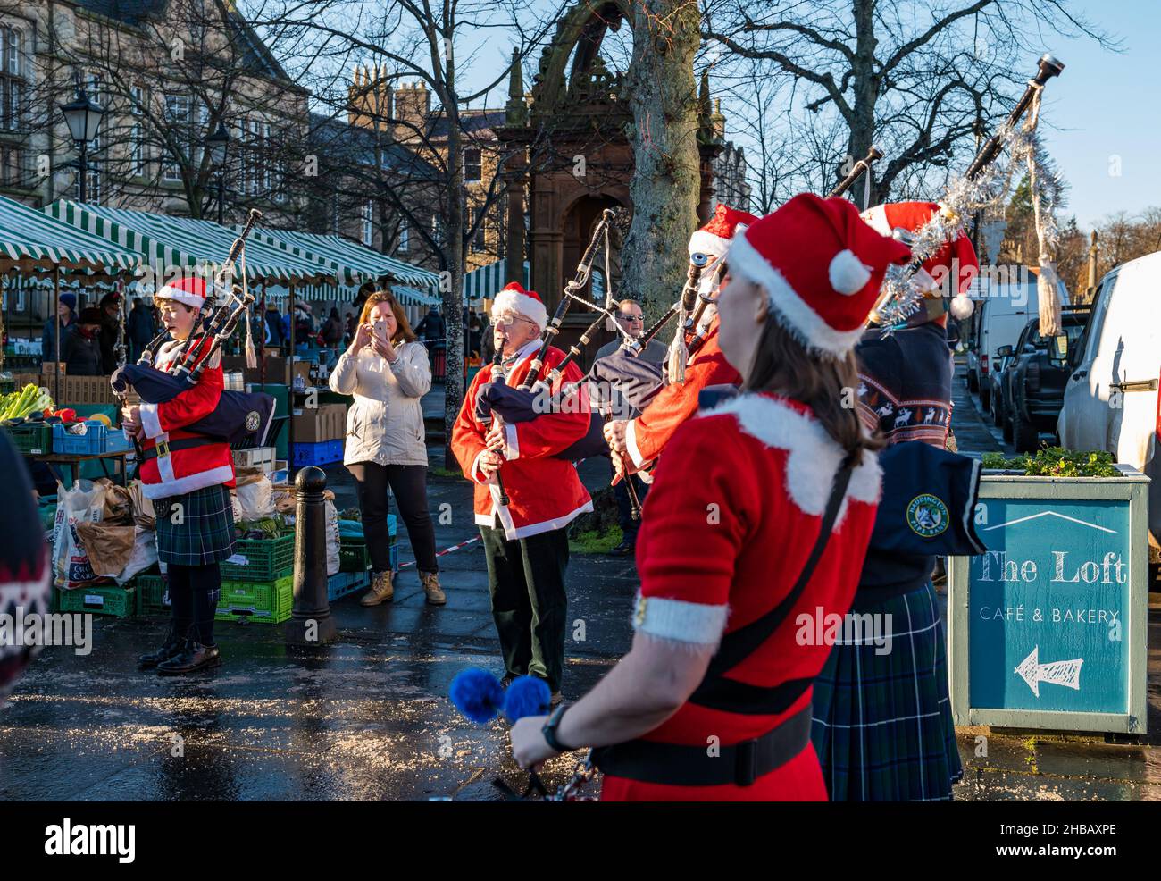 Haddington, East Lothian, Écosse, Royaume-Uni, 18th décembre 2021.Groupe de tubes de Noël : les membres du groupe de tuyaux de Haddington déguisent des costumes de Noël pour jouer au dernier des marchés fermiers mensuels pour cette année à court Street par une froide journée d'hiver ensoleillée Banque D'Images