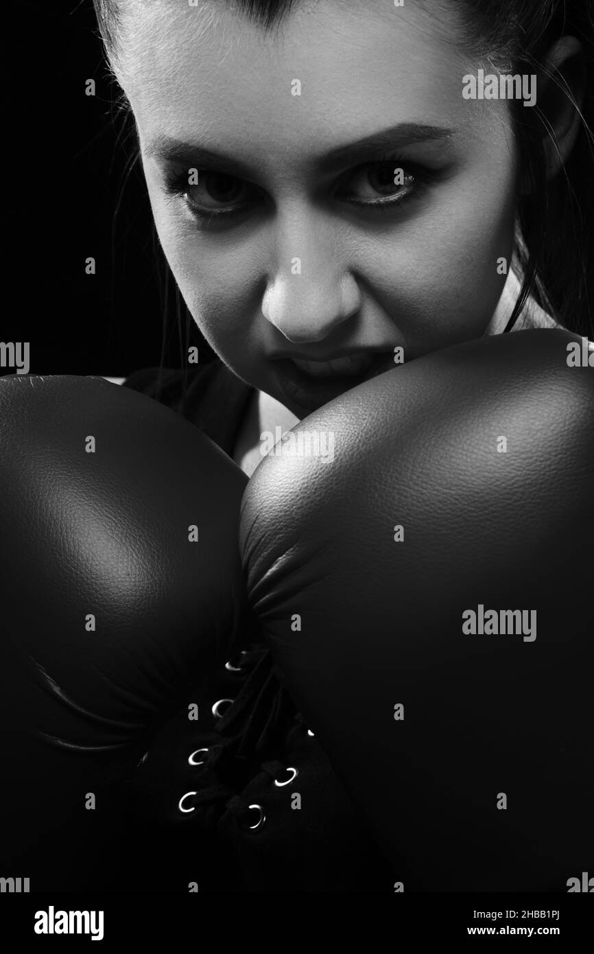 Muay Thai boxeur femelle dans la posture d'attaque. Fitness jeune femme entraînement de boxe sur fond noir, monochrome Banque D'Images