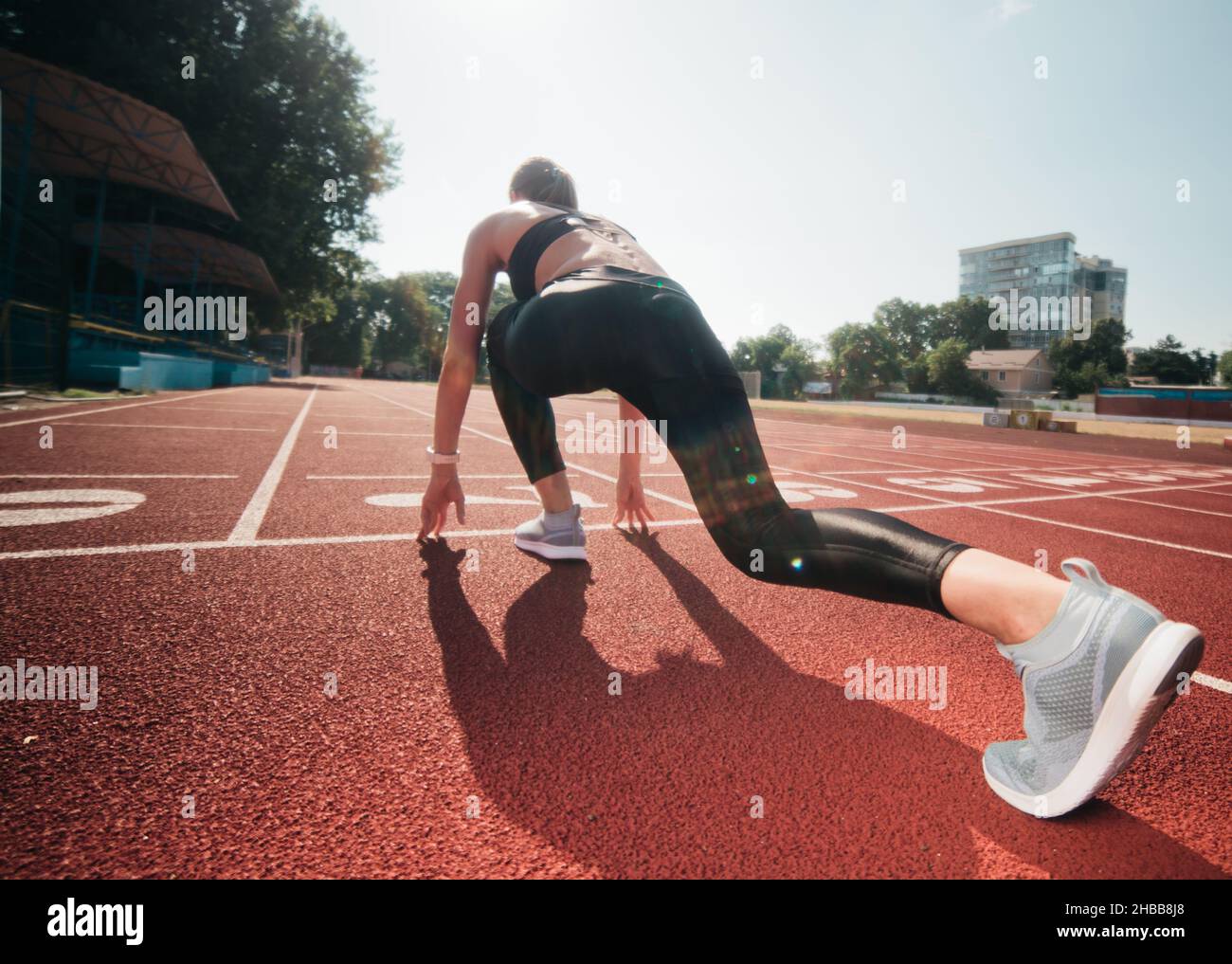 Femme coureur de vêtements de sport prêt à courir sprint à bas démarrage en extérieur.Vue arrière Banque D'Images