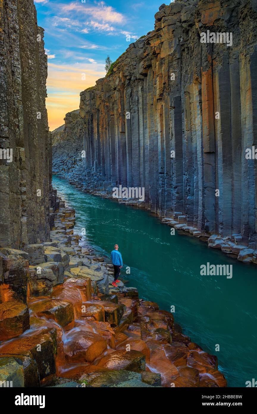 Randonneur se tenant au fond du canyon de Studlagil en Islande au coucher du soleil Banque D'Images