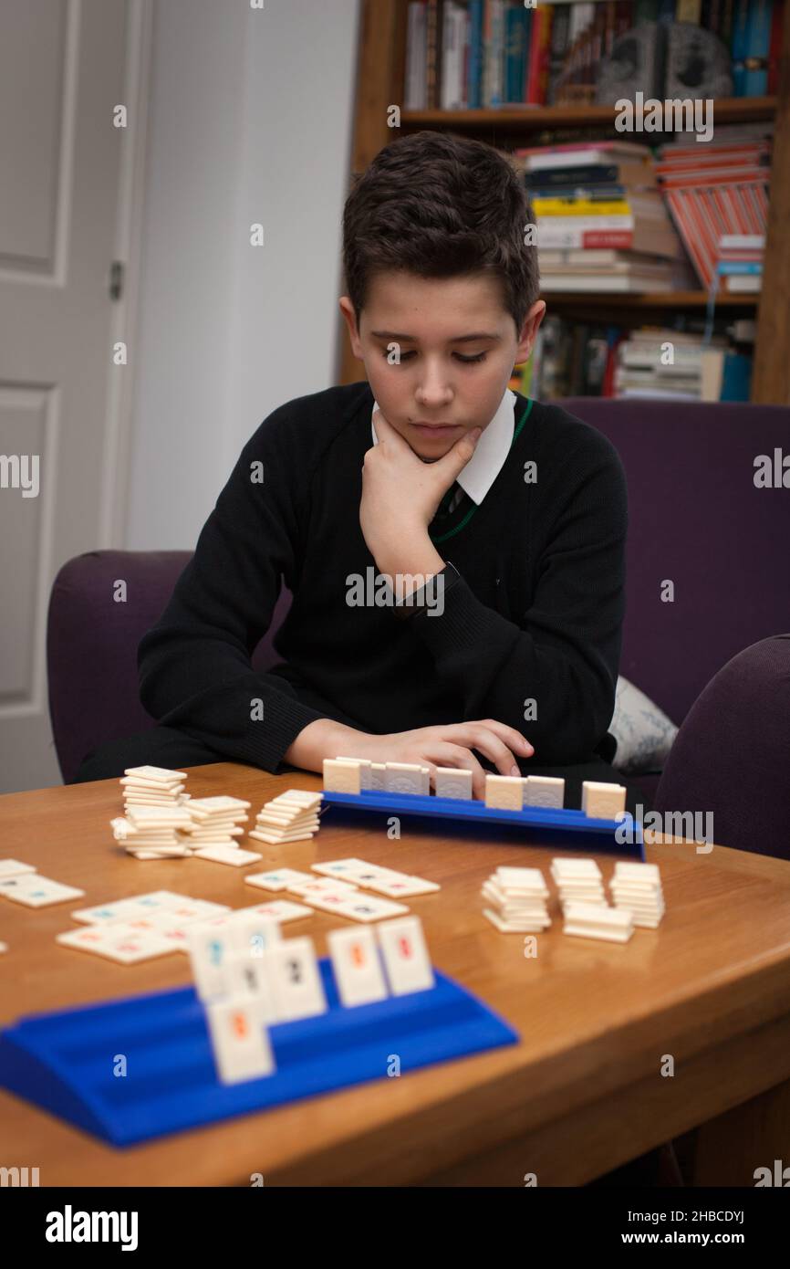 Un garçon jouant à Rummikub et pensant à son prochain jeu Banque D'Images