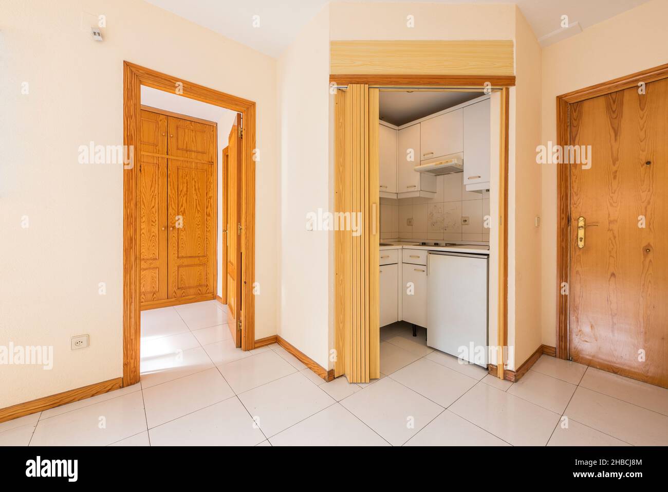 Cet appartement comprend une petite cuisine, une chambre avec une armoire en pin et du carrelage blanc Banque D'Images