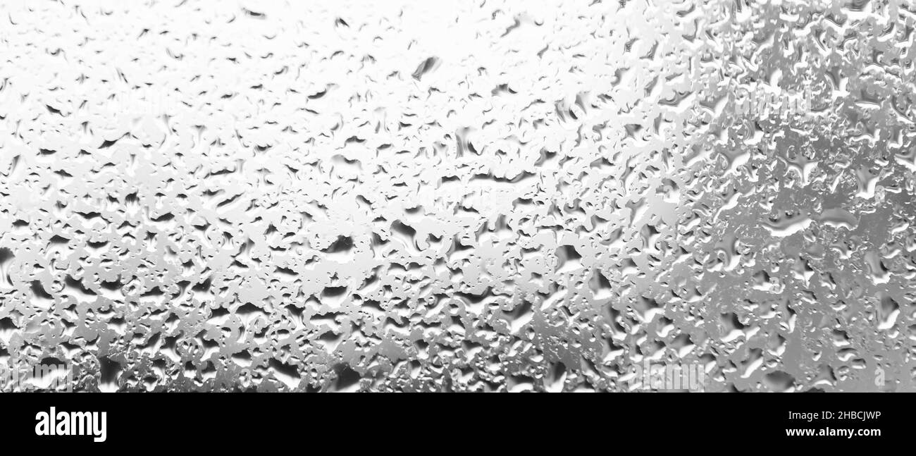 L'eau tombe derrière le verre.Arrière-plan des gouttes de pluie sur la fenêtre.Toile de fond noir et blanc faite de gouttes d'eau.Modèle créatif Banque D'Images