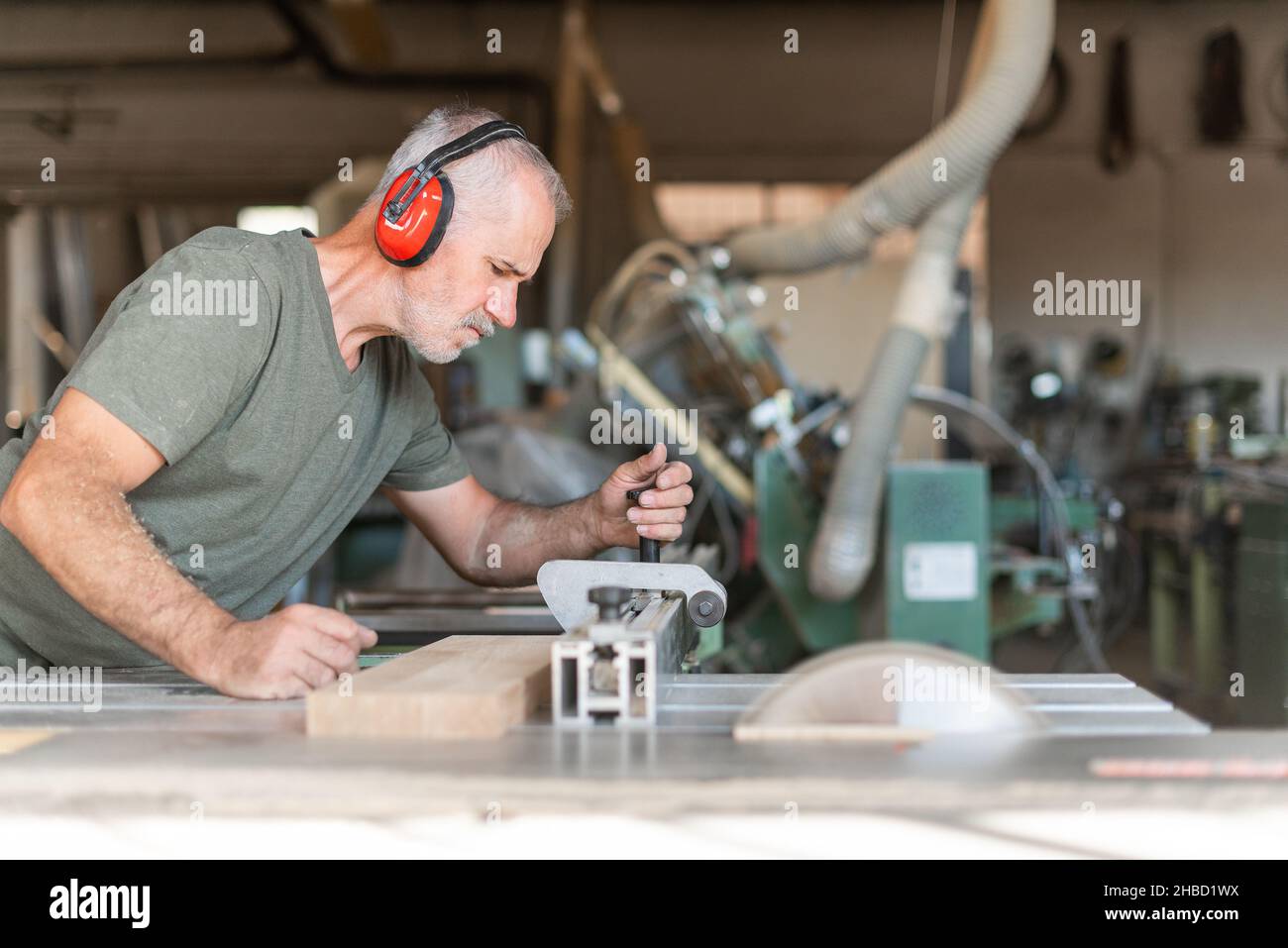 Travailleur coupant du bois avec précision sur une scie à table coulissante Banque D'Images