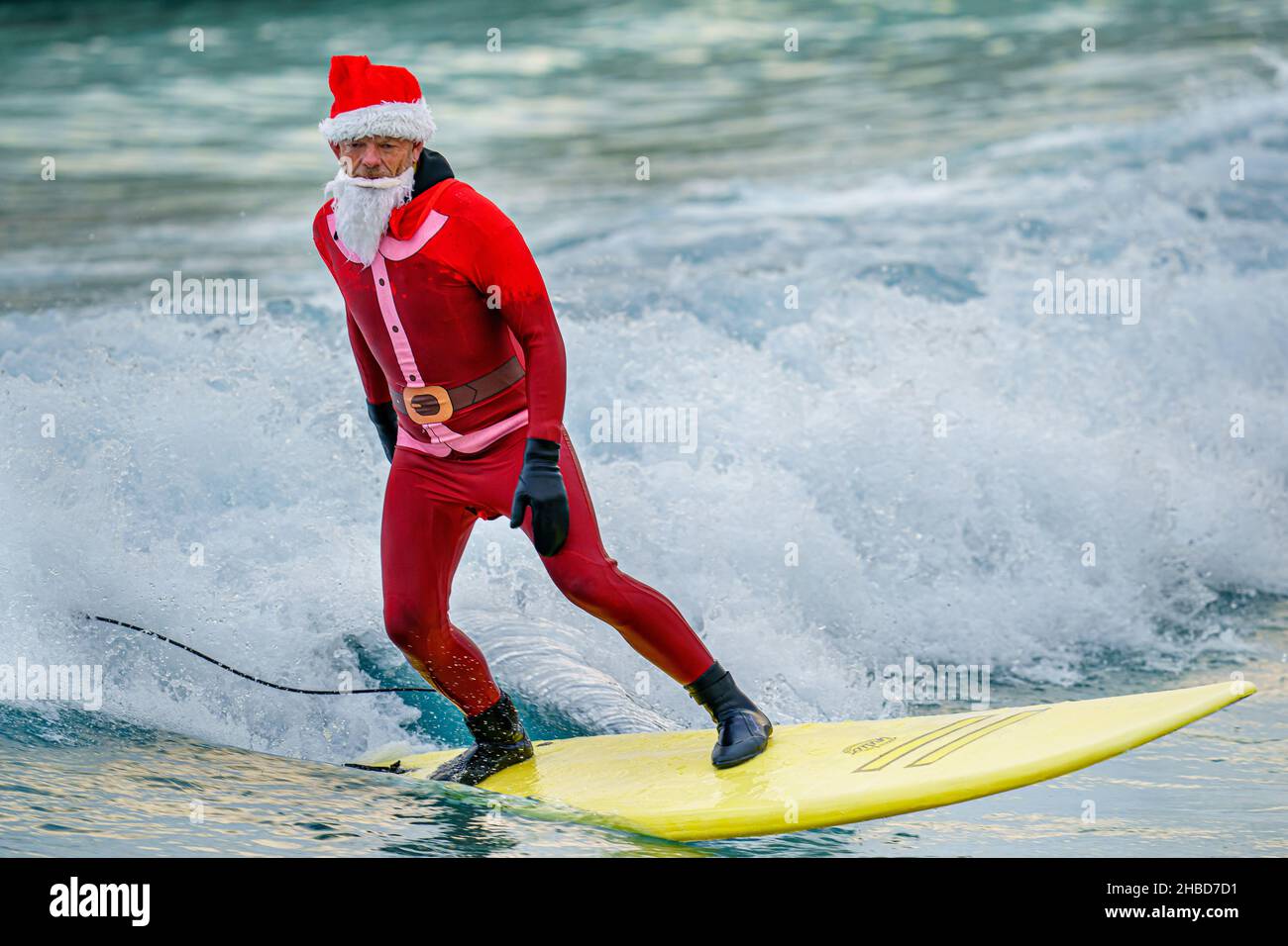 Un surfeur habillé comme le Père Noël fait une vague lors d'un Santa Surf organisé par l'organisme caritatif de surf The Wave Project, où les jeunes, qui connaissent une gamme de problèmes de santé physique et mentale, se rencontrent chaque année pour surfer avec leurs mentors au Wave à Bristol.Date de la photo: Samedi 18 décembre 2021. Banque D'Images