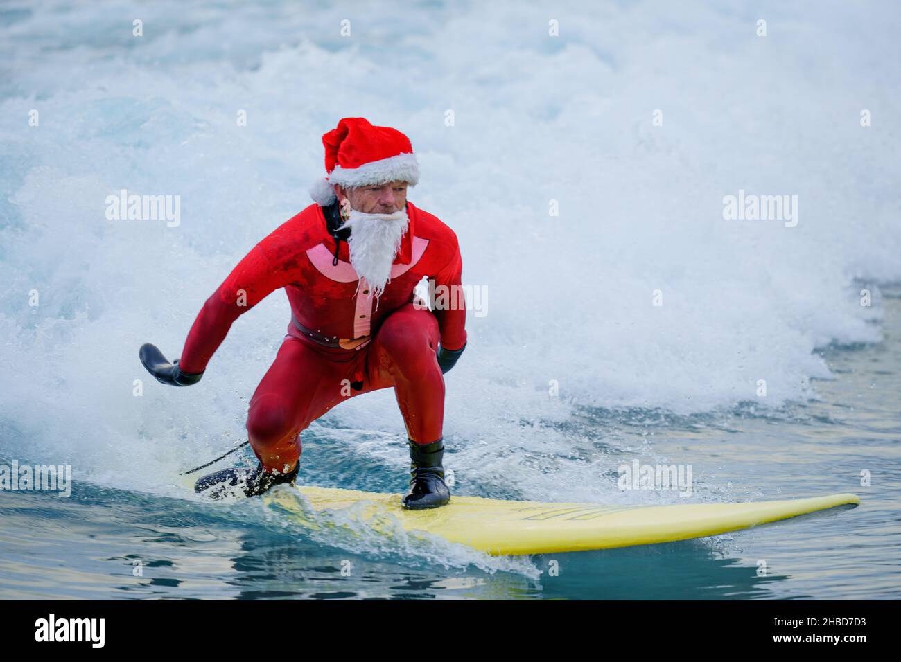 Un surfeur habillé comme le Père Noël fait une vague lors d'un Santa Surf organisé par l'organisme caritatif de surf The Wave Project, où les jeunes, qui connaissent une gamme de problèmes de santé physique et mentale, se rencontrent chaque année pour surfer avec leurs mentors au Wave à Bristol.Date de la photo: Samedi 18 décembre 2021. Banque D'Images