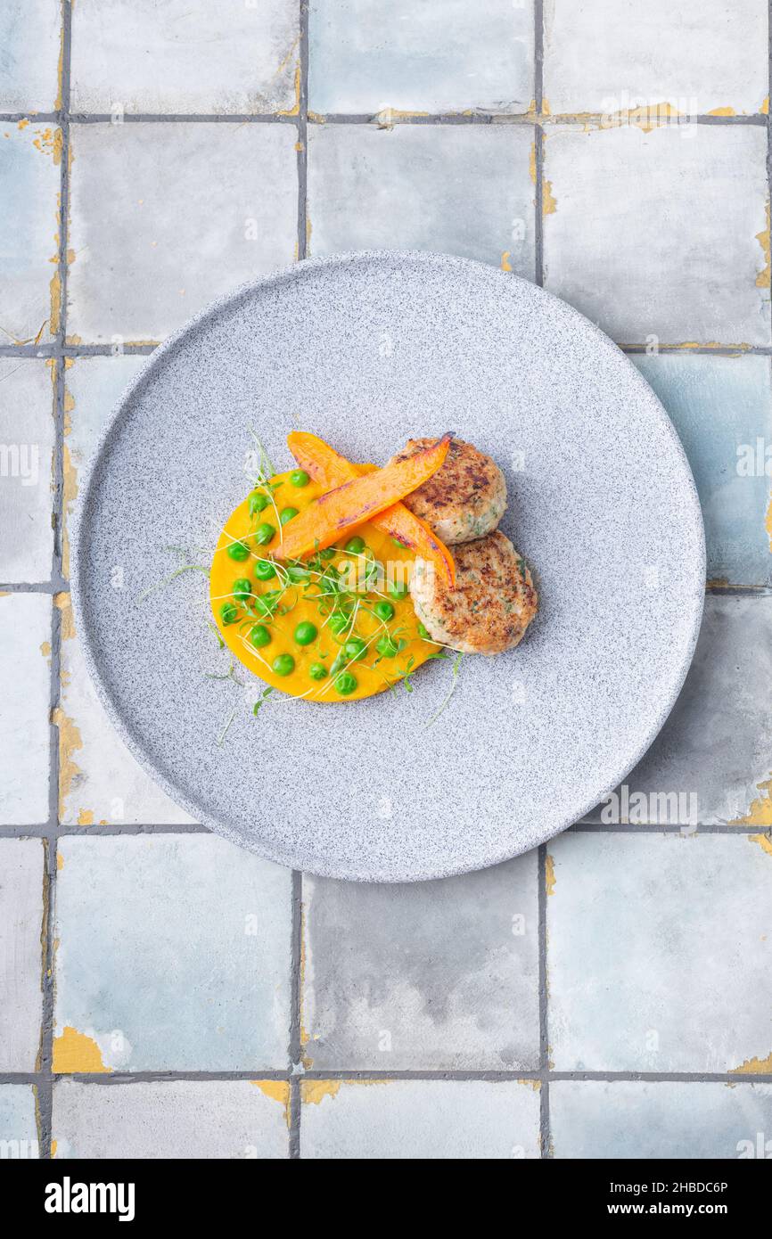 Côtelettes de poulet avec purée de citrouille et tartes vertes, ornées de carottes sur fond de carreaux Banque D'Images