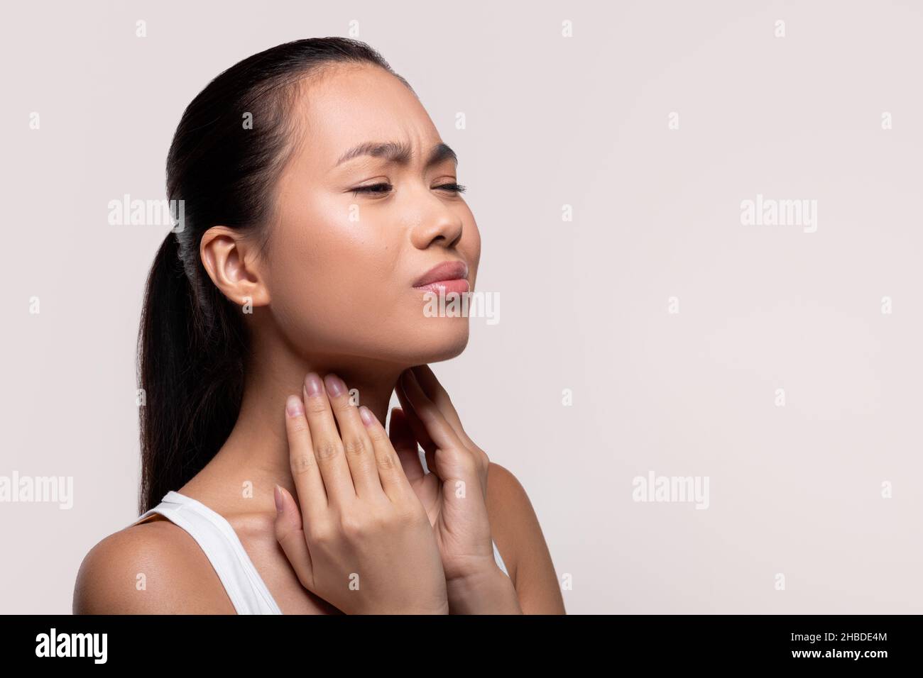 Femme asiatique souffrant de mal de gorge, touchant son cou Banque D'Images