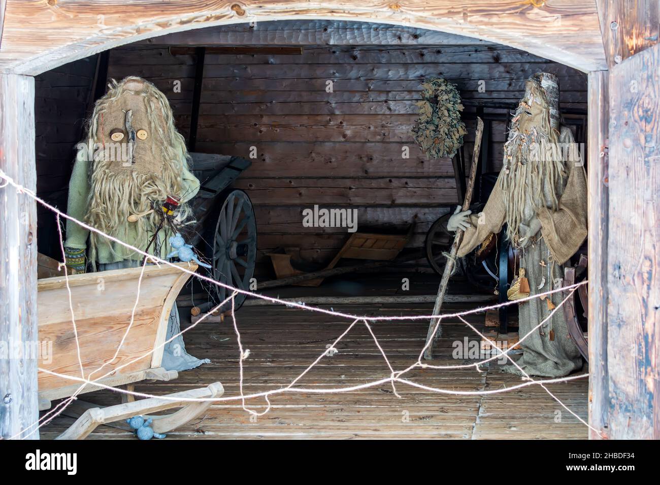 Poupées dans les masques de Meteņi et costumes de vieux hommes qui restent dans la vieille carrille-maison en bois Banque D'Images