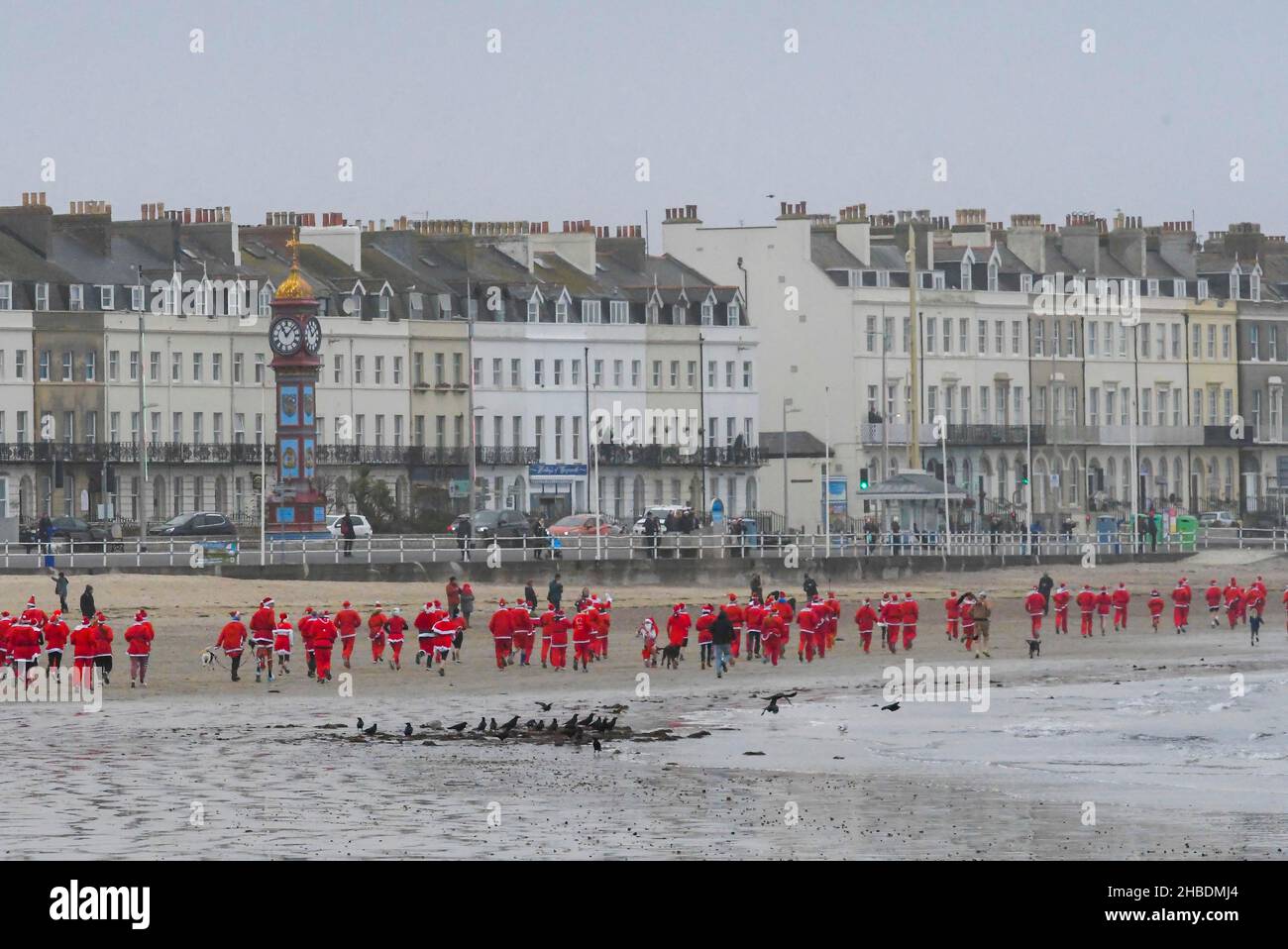 Weymouth, Dorset, Royaume-Uni.19th décembre 2021.Des centaines de coureurs vêtus de Santa prennent part à la course annuelle de pré-chistmas de Chase le Pudding sur la plage de Weymouth à Dorset.L'événement annuel est de recueillir de l'argent pour l'organisme de bienfaisance will Mackaness Trust.Coureurs sur la plage.Crédit photo : Graham Hunt/Alamy Live News Banque D'Images