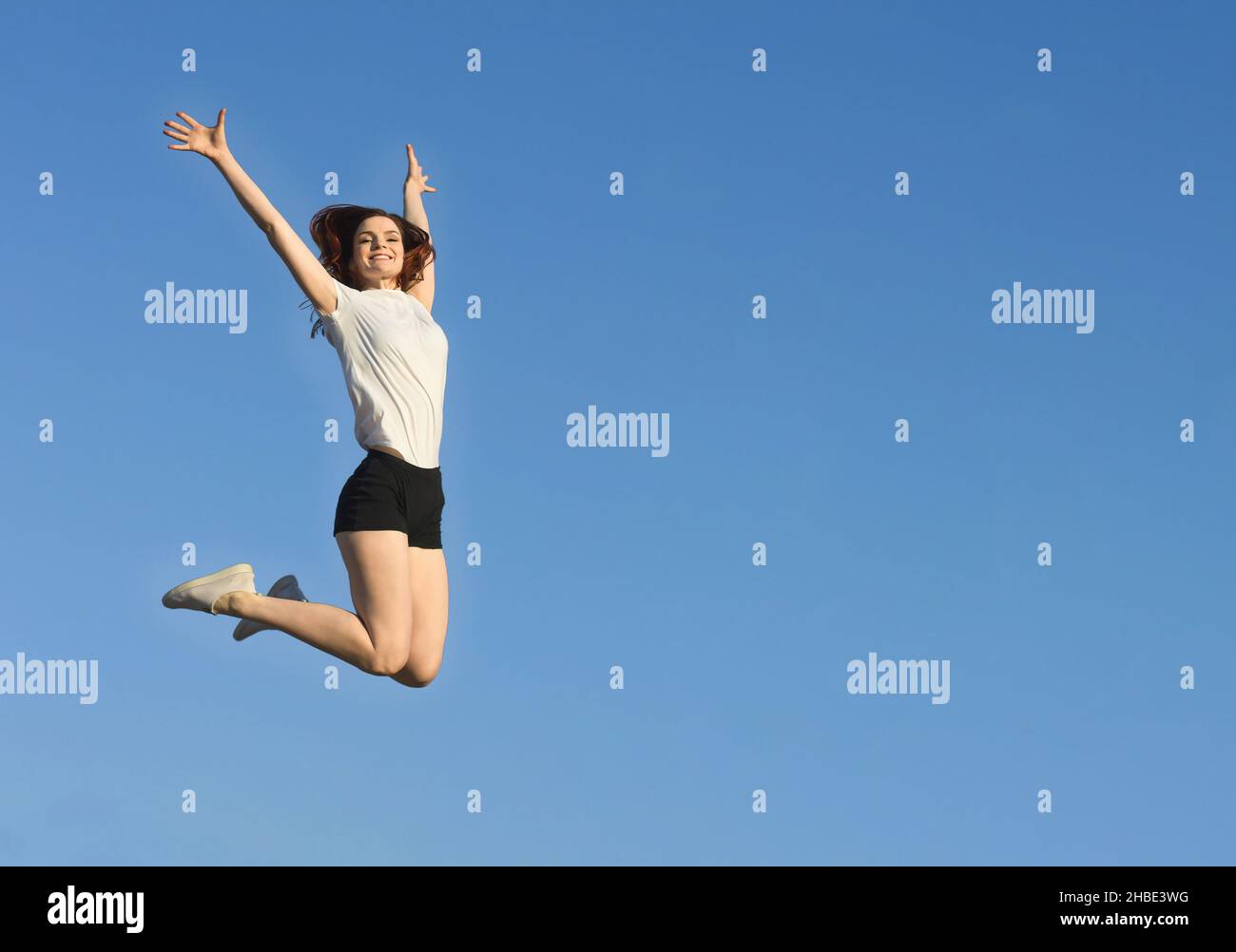 Femme mince saut.Gardez la forme.Fille sportive positive sur fond de ciel bleu. Banque D'Images
