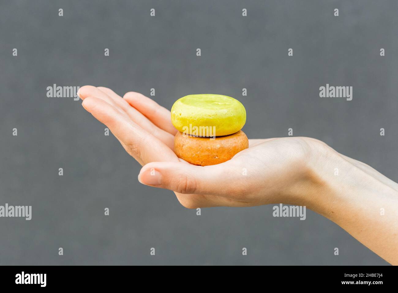 Mains de femme tenant du savon organique ou du shampooing solide sans emballage sur fond gris.Mode de vie sain, beauté, soins de la peau, concept zéro déchet. Banque D'Images