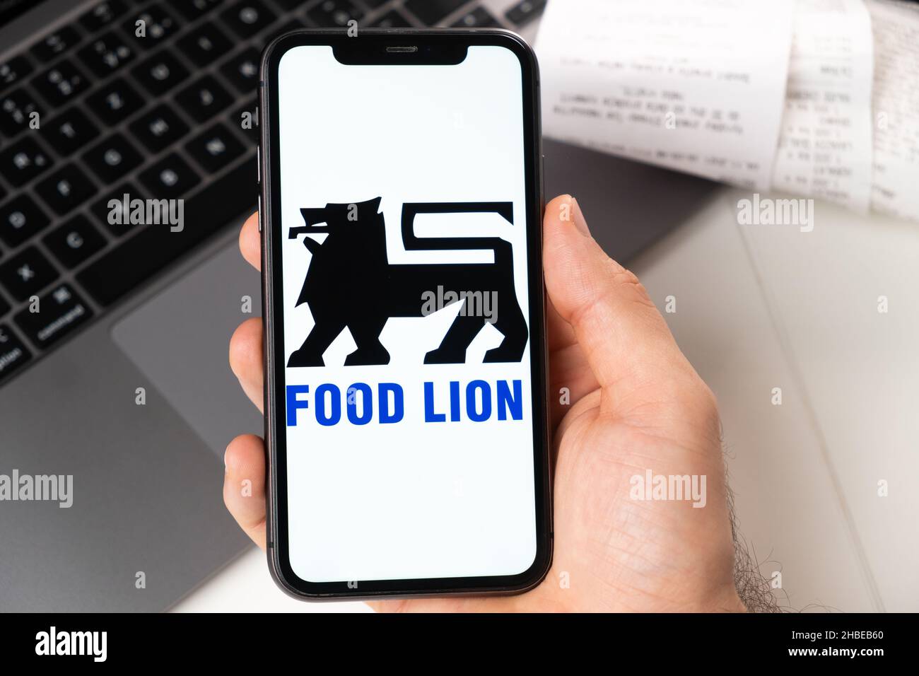 Application Food Lion d'un supermarché et d'une épicerie dans un smartphone.Un homme tient un smartphone avec une application pour faire du shopping et un ordinateur portable en arrière-plan.Novembre 2021, San Francisco, États-Unis Banque D'Images