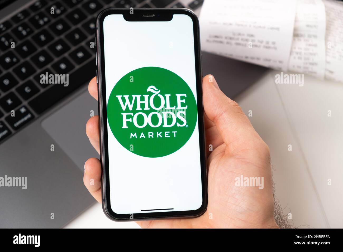 Application Whole Foods sur l'écran d'Apple iPhone dans la main de mans et ordinateur portable sur l'arrière-plan.Concept d'achat en ligne.Novembre 2021, San Francisco, États-Unis Banque D'Images