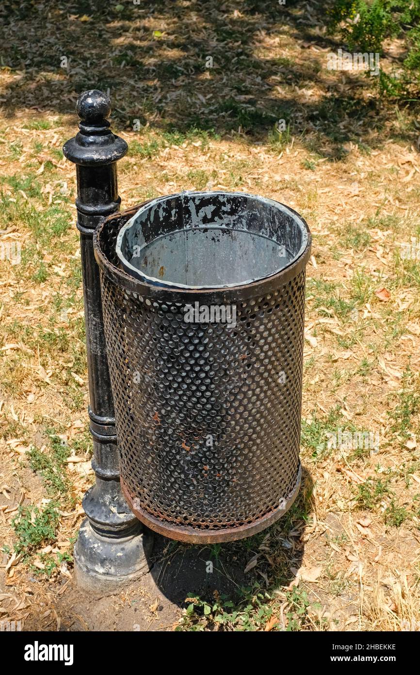 Poubelle en métal noir au poteau dans le parc Banque D'Images