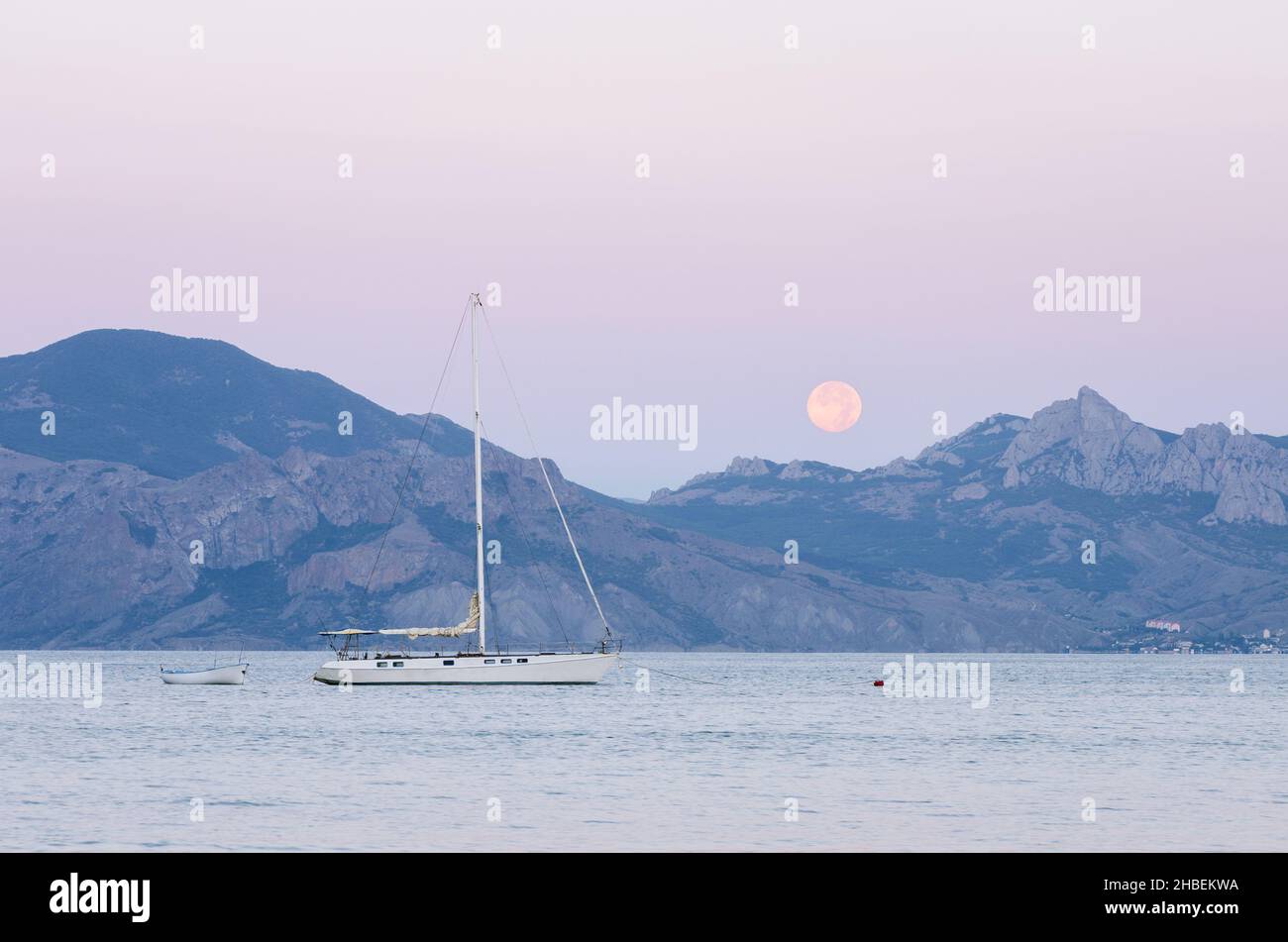Vue sur la mer avec yacht à voile.Pleine lune sur la crête.Paysage d'été au crépuscule près de la ville de la station Banque D'Images