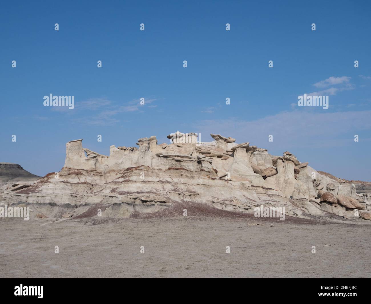 Un affleurement de roche beige érodée avec des tourteaux et des casquettes à Bisti Badlands ou de-Na-Zin Wilderness au Nouveau-Mexique avec des nuages clairsemés au-dessus. Banque D'Images