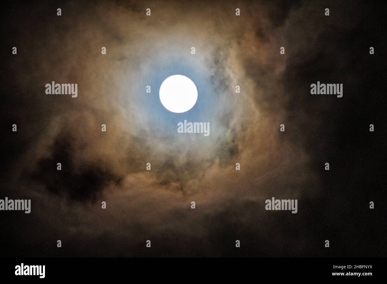 Une pleine lune qui regarde à travers les nuages. Banque D'Images