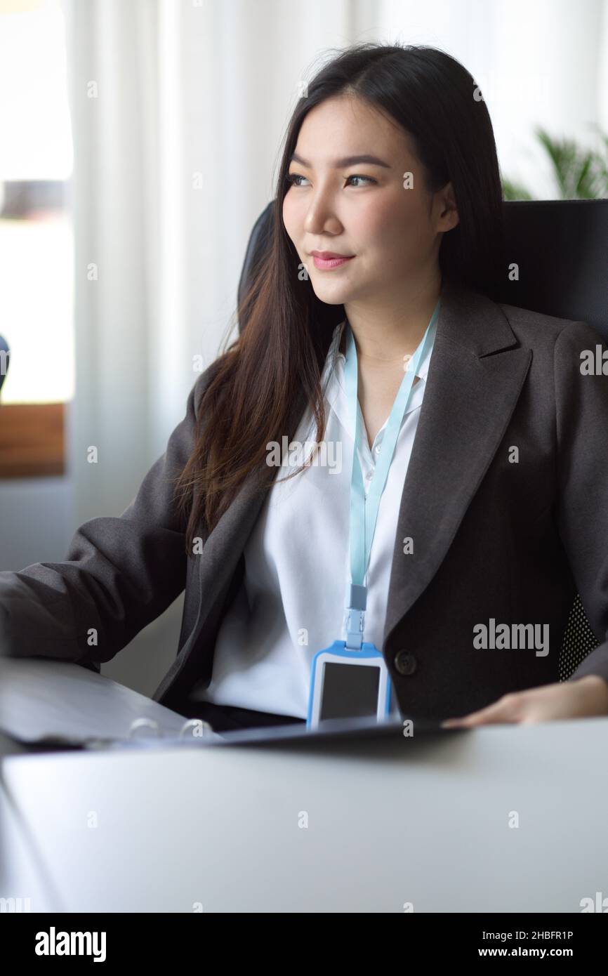 Portrait d'une jeune femme d'affaires asiatique assise à son bureau et rêvant d'un plan d'avenir de réussite, en regardant par la fenêtre. Banque D'Images