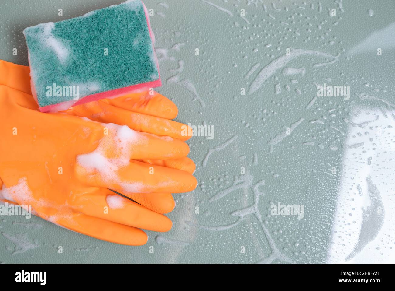 Gants avec éponge humide pour le nettoyage sur verre recouvert de mousse Banque D'Images