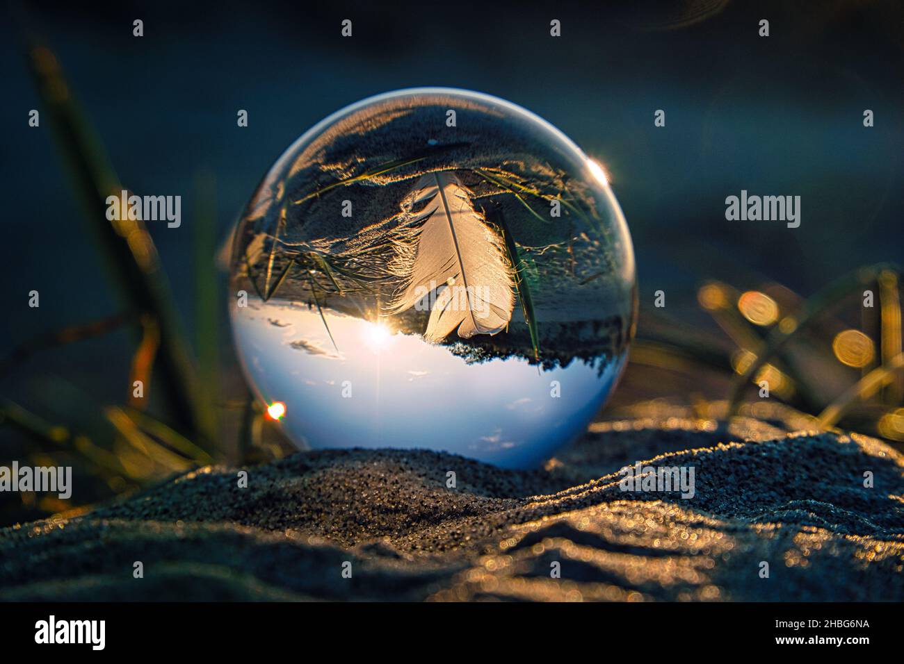 Boule de verre sur la plage de la mer Baltique à Zingst avec une plume représentée dans le ballon avec le paysage.Le coucher du soleil offre une ambiance chaleureuse Banque D'Images