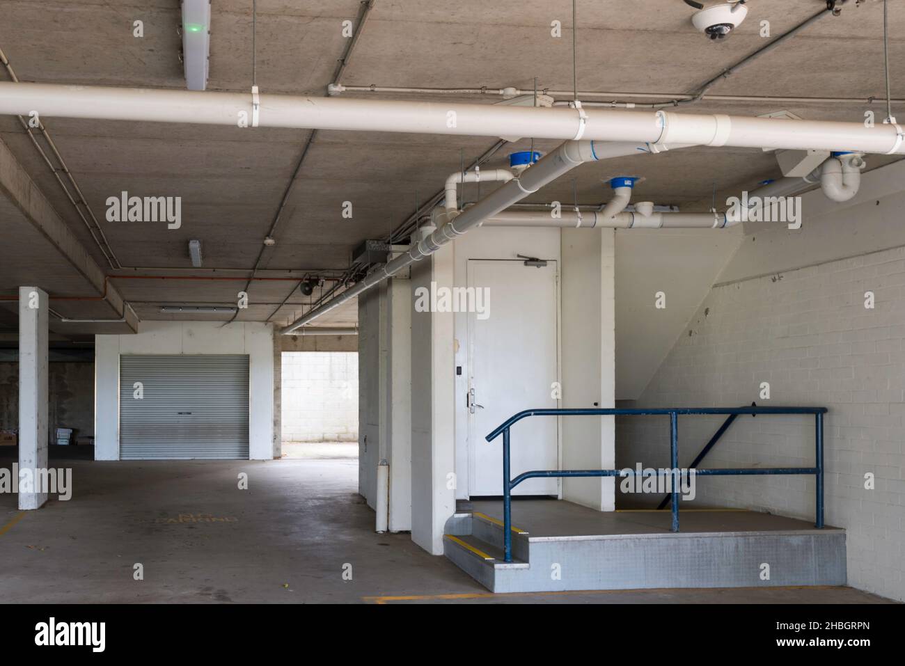 Tuyaux de plomberie en PVC exposés sous le plancher dans un parking couvert sous un bâtiment commercial à Sydney, en Australie Banque D'Images