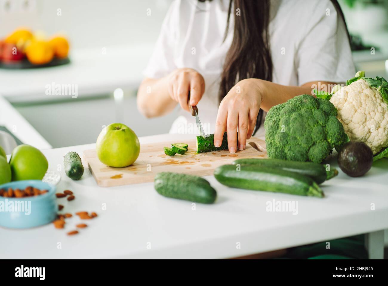 Femme préparant de la nourriture dans sa cuisine.Une femme hache des légumes verts frais sur une planche à découper dans une cuisine légère.Alimentation saine, désintoxication, alimentation Banque D'Images