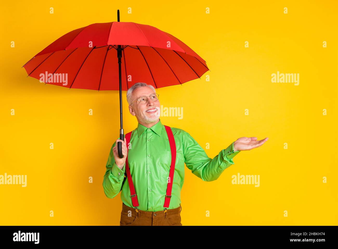 Photo de l'homme âgé sourire heureux positif protéger parapluie de pluie automne isolé sur fond jaune de couleur Banque D'Images