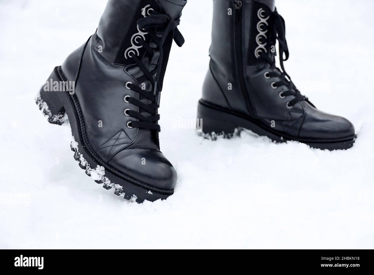 Jambes de femme en cuir noir bottes à lacets sur la neige.Femme sur la rue  d'hiver, chaussures chaudes pour temps froid Photo Stock - Alamy