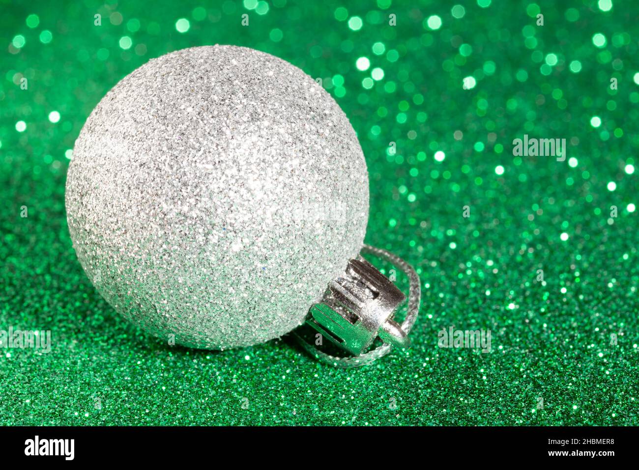 boule de noël argentée sur fond vert étincelant Banque D'Images