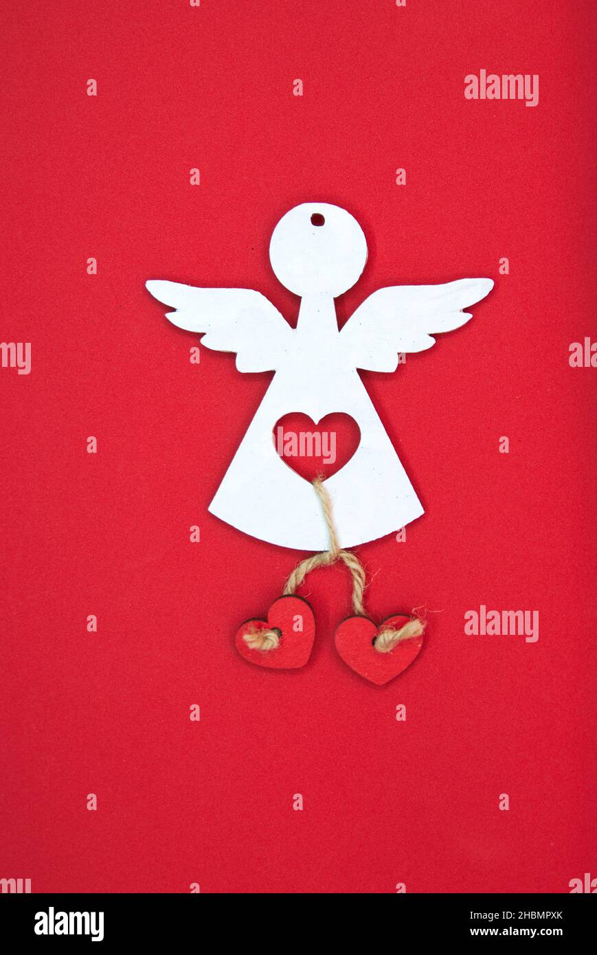 Ange blanc de Noël mignon avec coeurs rouges sur fond de studio.Saint Symbol avec ailes ; concept des vacances d'hiver à venir. Banque D'Images