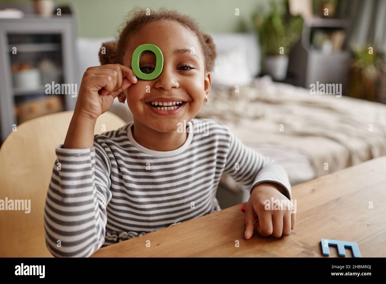 Portrait d'une adorable fille afro-américaine jouant avec des lettres et souriant à l'appareil photo, espace de copie Banque D'Images