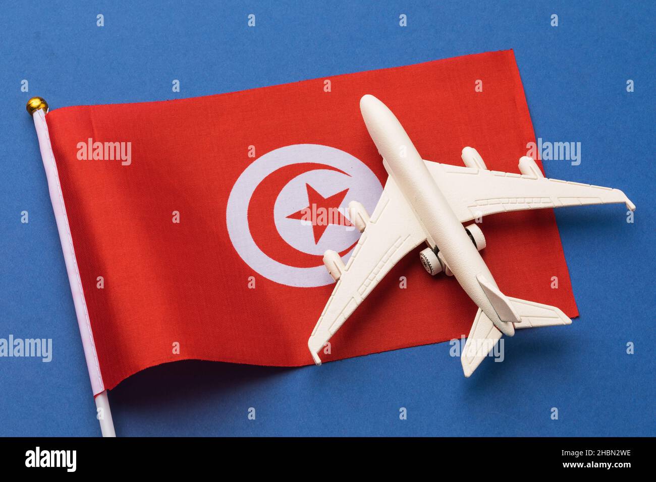 Drapeau tunisien et avion jouet sur fond coloré, concept sur le thème du voyage en Tunisie Banque D'Images