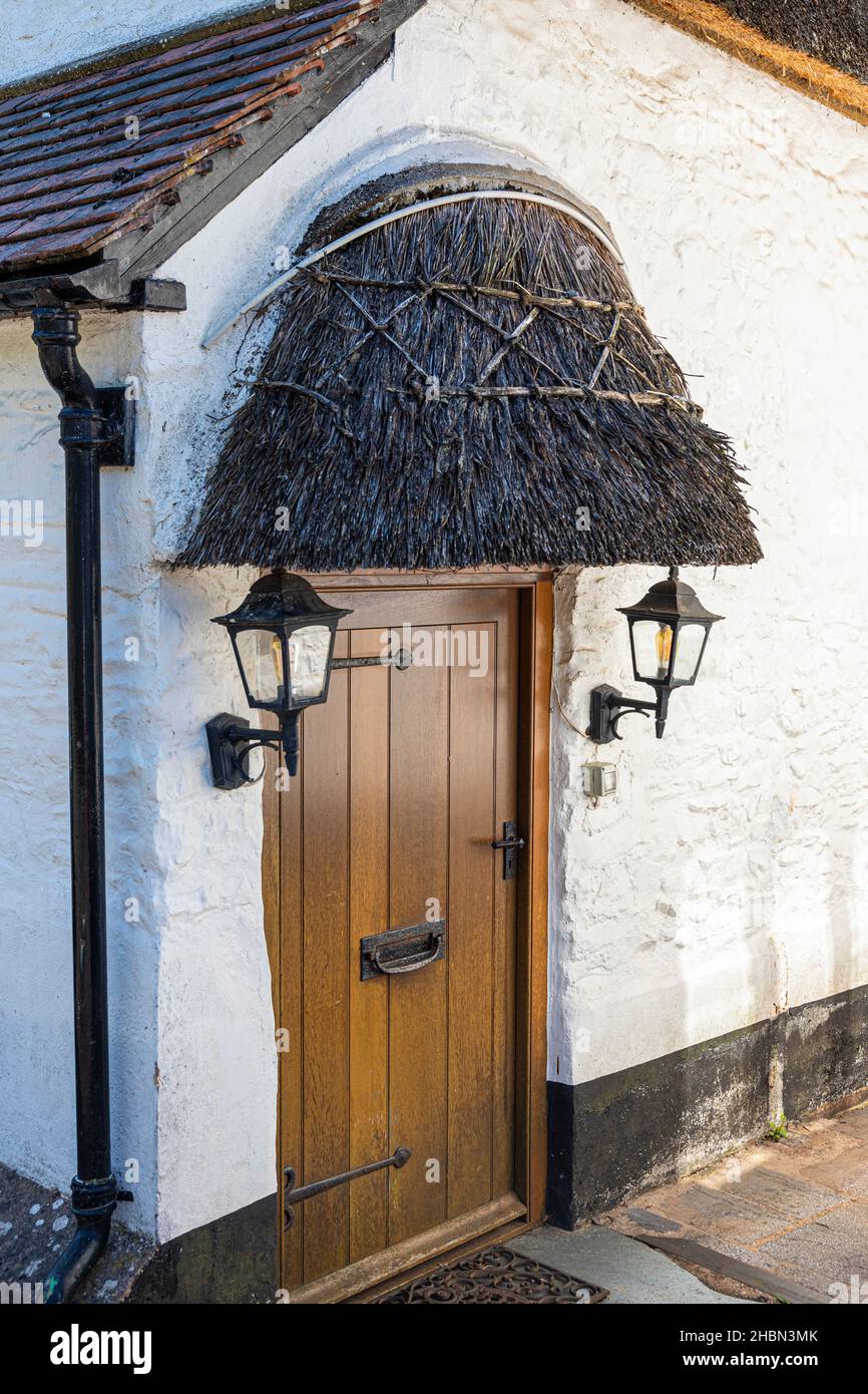 Une porte de chalet avec un petit porche en chaume dans le village Exmoor de Porlock, Somerset UK Banque D'Images