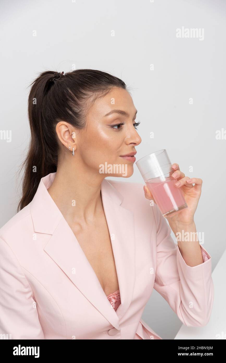 Salisbury, Royaume-Uni.2021. Portrait d'une femme avec un verre contenant une boisson liquide rose. Banque D'Images