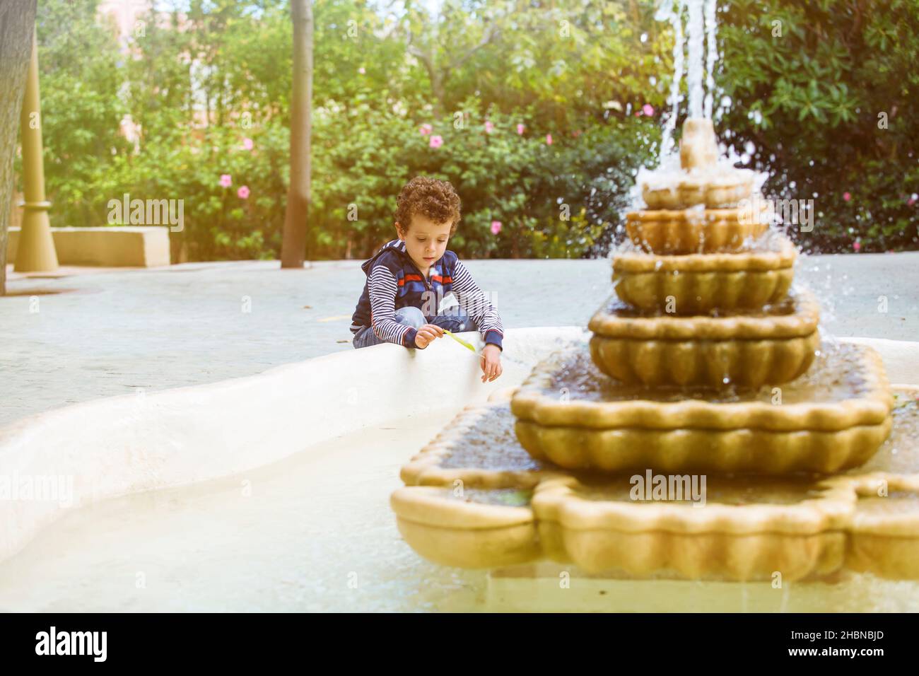 enfant jouant avec une feuille dans une fontaine Banque D'Images