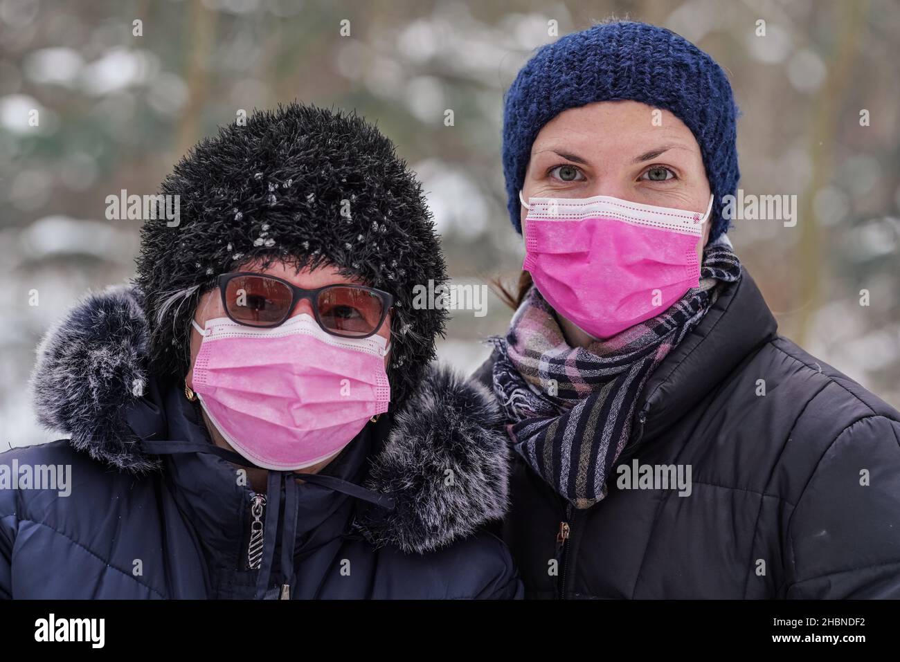 Femme âgée âgée avec sa fille plus jeune dans des vêtements chauds d'hiver, les deux portant un masque rose à usage unique et jetable virus Banque D'Images