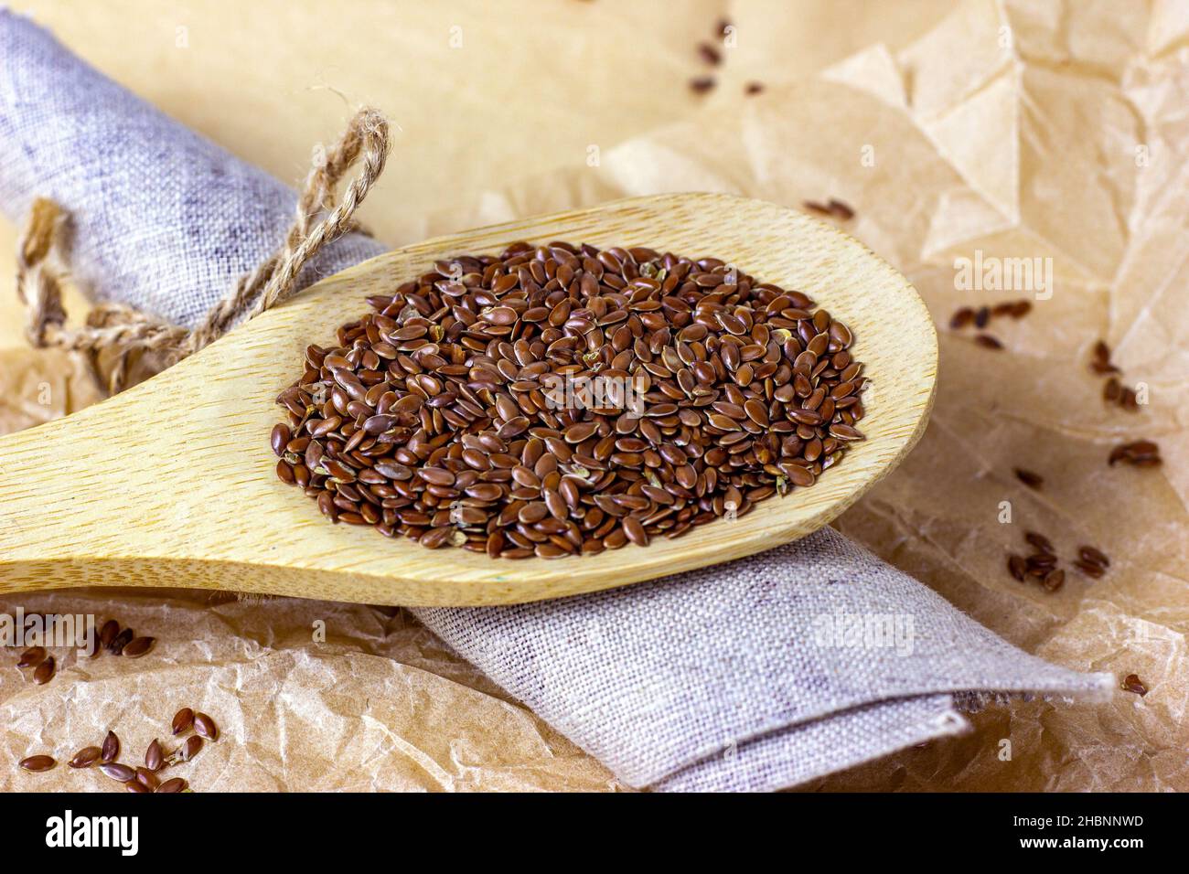 Faire dorer les graines de lin sèches dans une cuillère en bois sur un fond clair. Banque D'Images