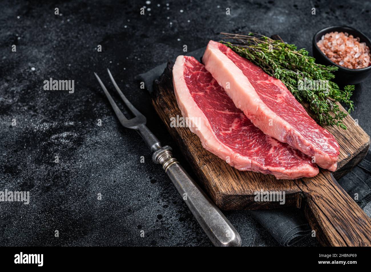 Steak de rumsteck cru non cuit ou biftecks de viande de bœuf au chapeau de sirloin sur une planche de bois. Arrière-plan noir. Vue de dessus. Copier l'espace Banque D'Images
