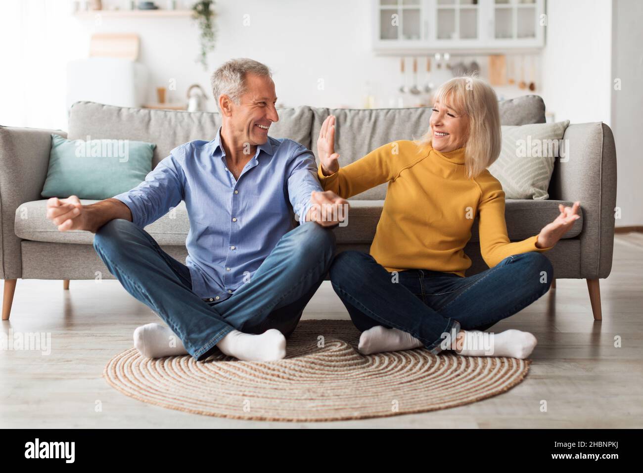 Couple mature faisant du yoga assis dans la position de Lotus à la maison Banque D'Images