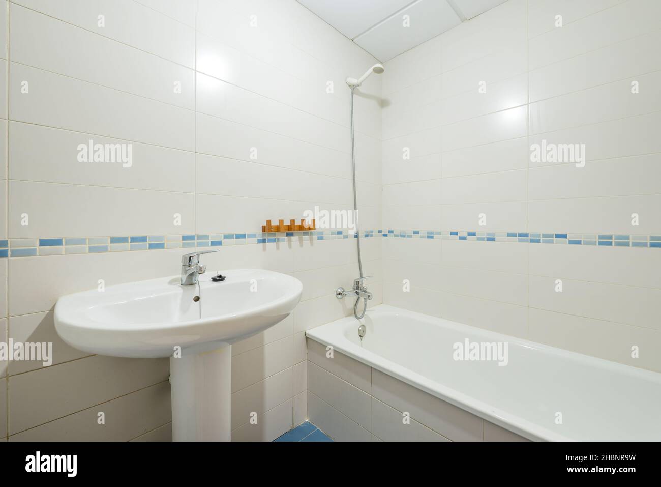 Toilettes avec lavabo blanc et baignoire et bordure en porcelaine bleue dans un appartement de location de vacances Banque D'Images