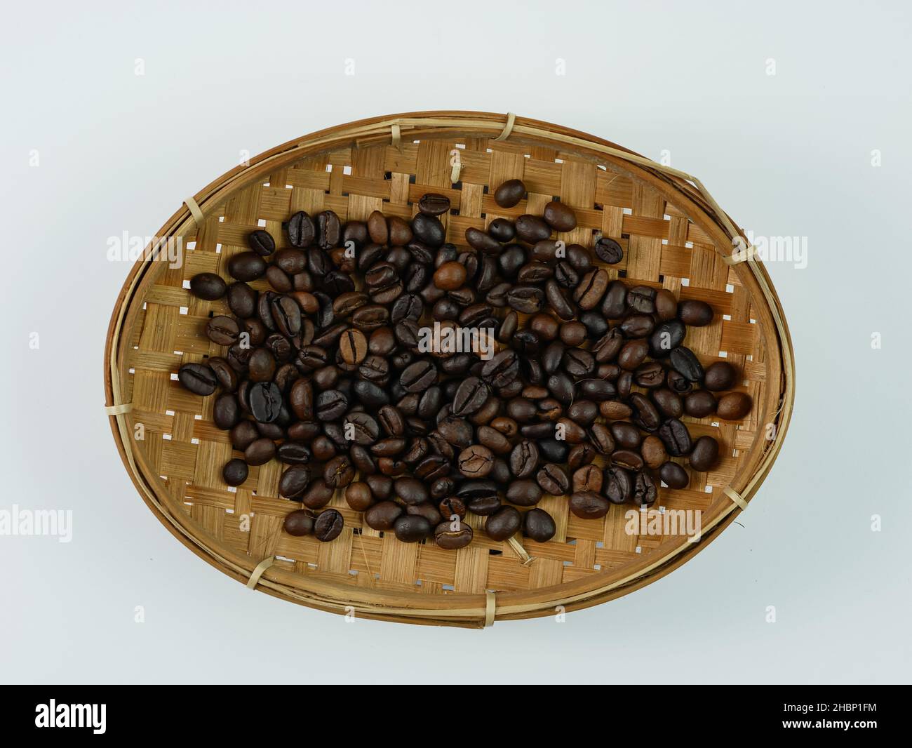 Grains de café de qualité dans un panier en bambou isolé sur fond blanc Banque D'Images